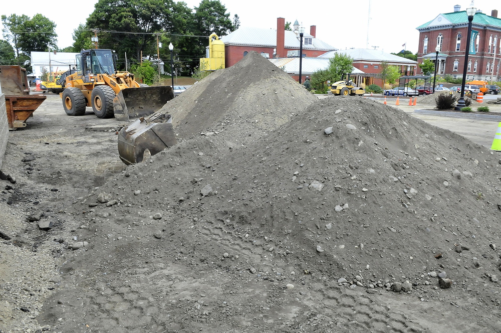 Contractors prepare to resurface the municipal parking lot in Skowhegan. The remains of a building and other debris near the piles of gravel were exposed during work behind the Hight car dealership.