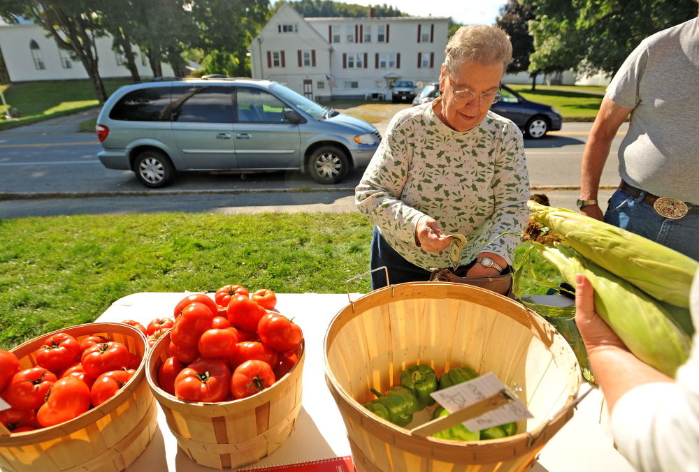Mary Wade buys corn at the farm stand on Main Street in Bingham on Thursday. The Good Shepherd Food Bank in collaboration with Maine Federation of Farmers’ Markets created the farm stand to offer discounted produce in rural Maine, where farmers markets can be impractical.