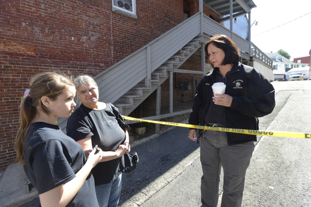 Fire victim Carrie Chenery, center, and granddaughter Keauna Froehlich, 14, talk with state fire investigator Mary MacMaster on Friday as they and other residents try to reclaim personal items from their apartments in Biddeford.