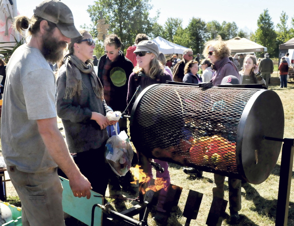 Dan Price of Freedom Farm demonstrates roasting peppers  in a gas — heated rotisserie to curious onlookers during the three-day Common Ground Country Fair in Unity, which opened Friday.