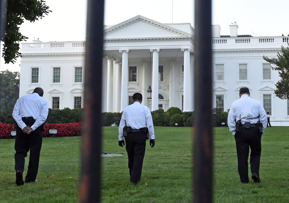 Uniformed Secret Service officers walk along the lawn on the North side of the White House in Washington on Saturday. The Secret Service is coming under renewed scrutiny after a man scaled the White House fence and made it all the way through the front door before he was apprehended.