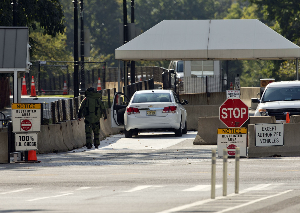An explosive technician in a bomb suit approaches a vehicle near the entrance to White House in Washington, Saturday.