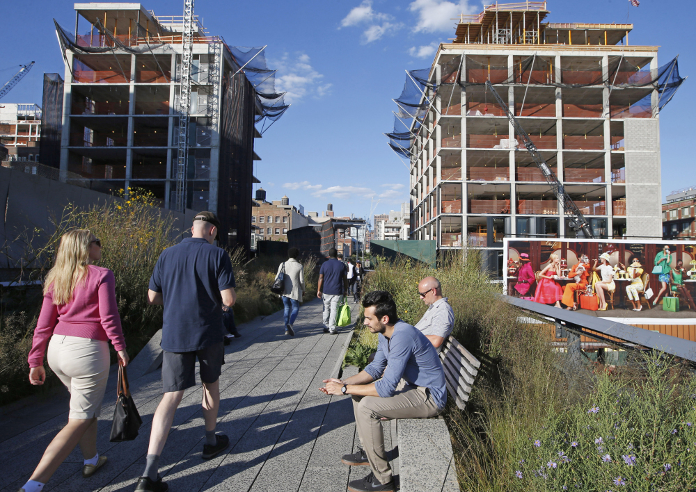 Pedestrians stroll along the High Line in New York as it winds between two buildings under construction. The last stretch of the elevated walkway opens to the public Sunday.