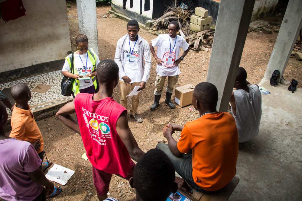 In this photo taken on Friday, Idrissa Kargbo, top right, Sierra Leone’s national marathon champion, helps volunteers distribute information on Ebola in Freetown, Sierra Leone.