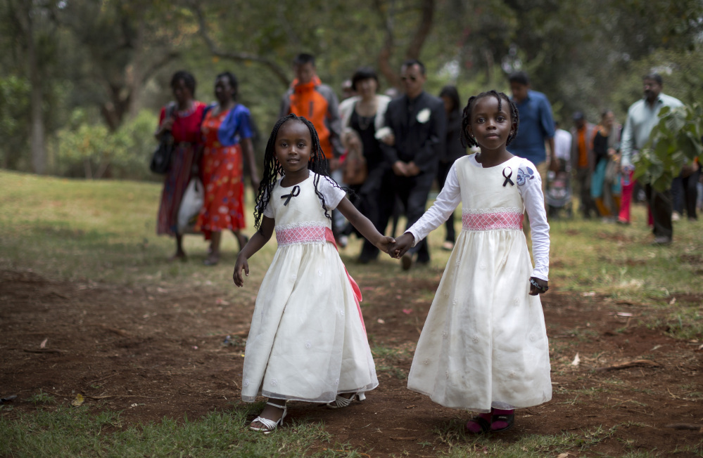 Gloria, 4, left, whose father, Christopher Chewa, was killed in the Westgate Mall attack, walks with her cousin, Miriam, 6, and other families of the victims to lay flowers and remember at the Amani Garden memorial site in the Karura Forest in Nairobi, Kenya on Sunday. Kenya is marking one year since four gunmen stormed the upscale Westgate Mall in Nairobi, killing 67 people.