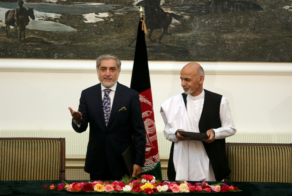 Afghanistan’s presidential election candidates Abdullah Abdullah, left, and Ashraf Ghani Ahmadzai, right, prepare to leave after signing a power-sharing deal at the presidential palace in Kabul, Afghanistan, on Sunday. Afghanistan’s two presidential candidates signed a power-sharing deal, capped with a hug and a handshake, three months after a disputed runoff that threatened to plunge the country into turmoil and complicate the withdrawal of U.S. and foreign troops.