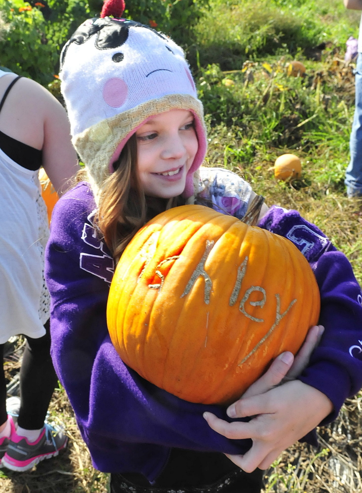 Albert S. Hall school student Ashley Harwood holds her pumpkin engraved with her name on Thursday after she and her fellow students donated onions to the Mid-Maine Homeless Shelter.