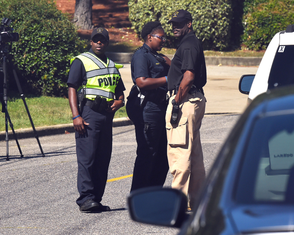 Police officers confer near the scene where three people were killed, including the gunman, at a UPS facility in Birmingham, Ala., on Tuesday.