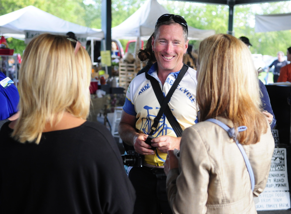 Glenn Charles chats with marketgoers Tuesday during an event at the farmers market at Mill Park in Augusta. He is on a bicycle tour to learn about food in New England.