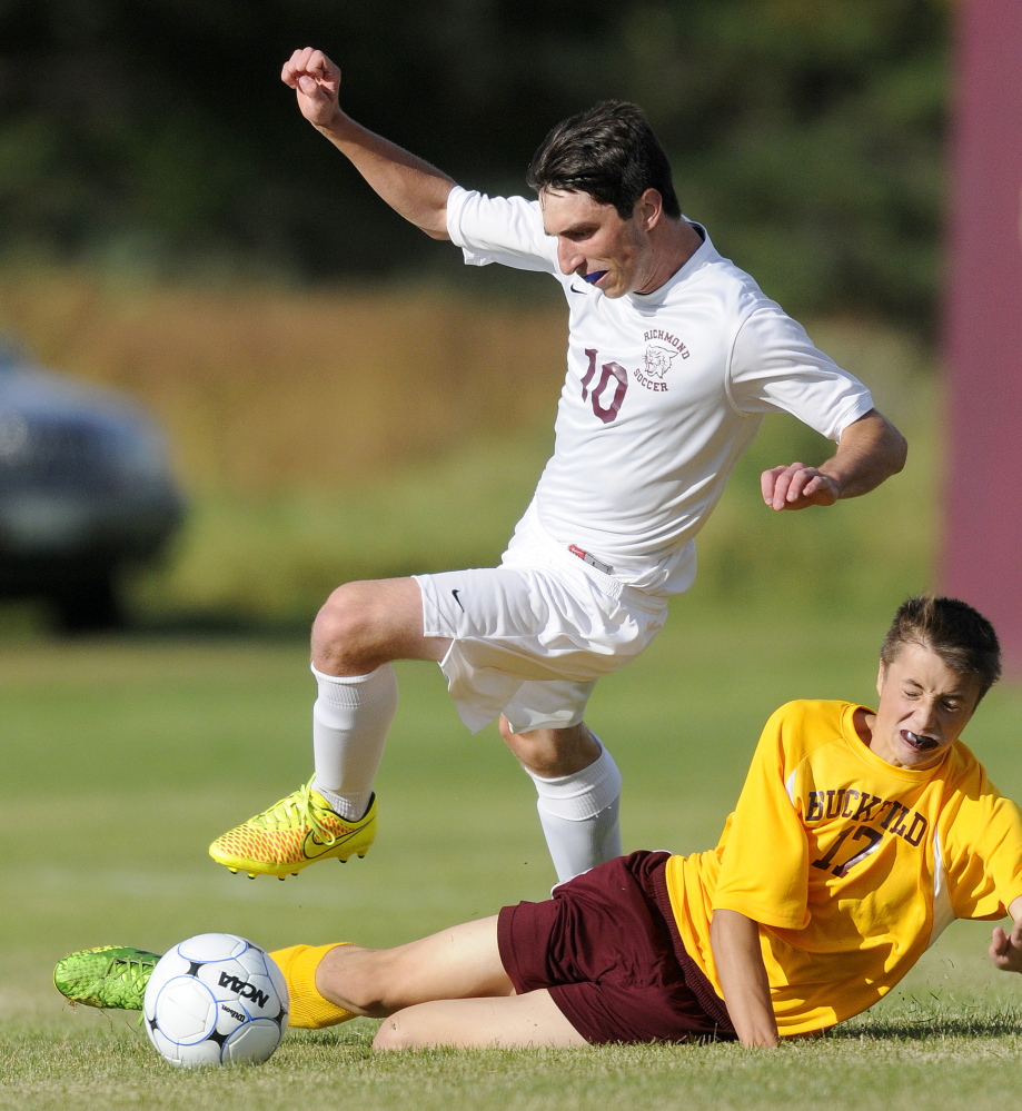 Richmond High School junior Tyler Soucy, left, leaps to avoid Buckfield defender Sidney Jackson during a Western D boys soccer game Tuesday. The Bobcats prevailed 2-1.