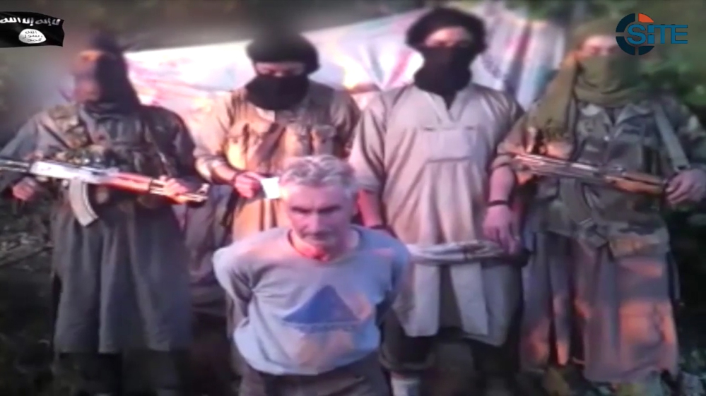 In this still image from video posted on the Internet on Wednesday by a group calling itself Jund al-Khilafah, Soldiers of the Caliphate, members of the group stand behind French mountaineer Herve Gourdel just before beheading him. In the video, the men pledge their allegiance to the leader of the Islamic State group, Abu Bakr al-Baghdadi, before killing Gourdel, 55, whom they abducted on Sunday.