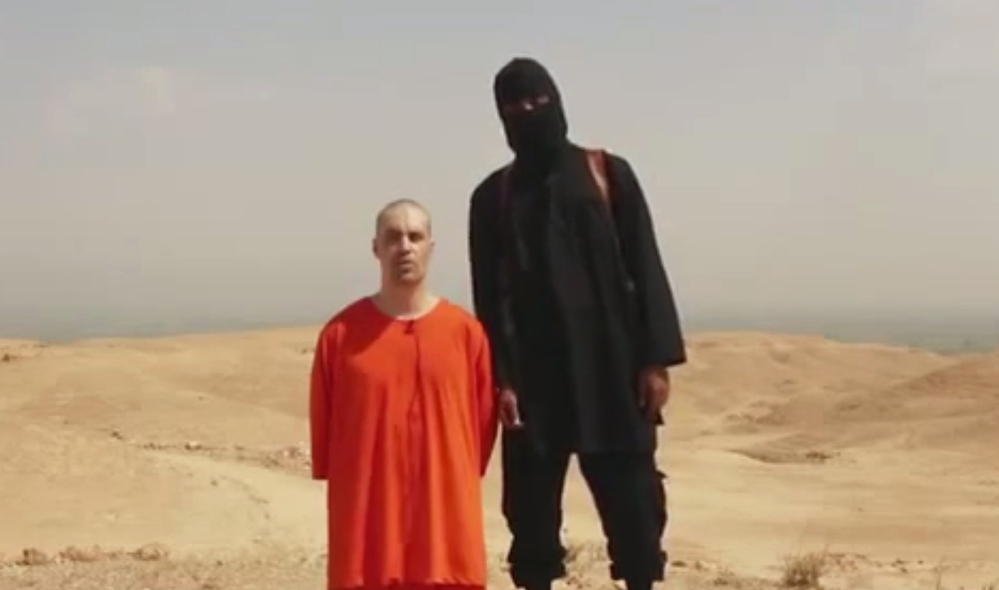 This frame from a video shows American journalist James Foley and a British-accented masked man whom the FBI says it may have identified.