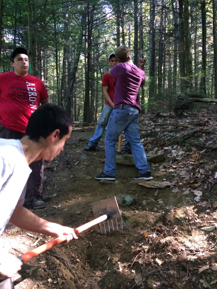 A crew from Marti Stevens Learning Center in Skowhegan installs a stepping stone to reduce wear on Pinnacle Trail at Lake George as part of a public service project.