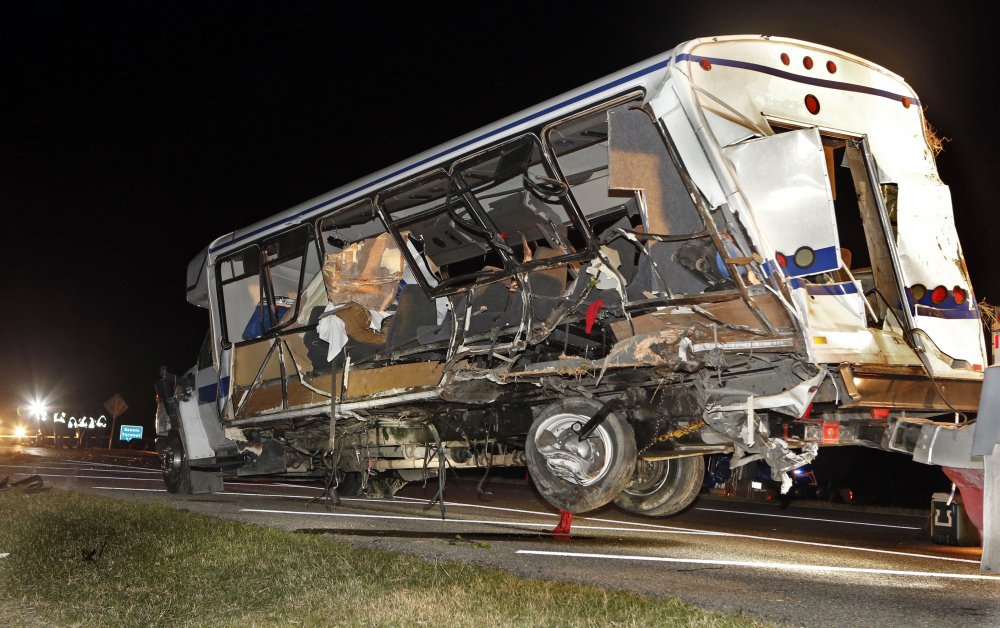 A wrecker removes the team bus as Highway Patrol and emergency personnel work the scene of a fatality accident just south of the Turner Falls area on Saturday.  Four members of a Texas college softball team died after a tractor trailer crossed over the center median on Interstate 35 and collided with the team’s bus Friday night.