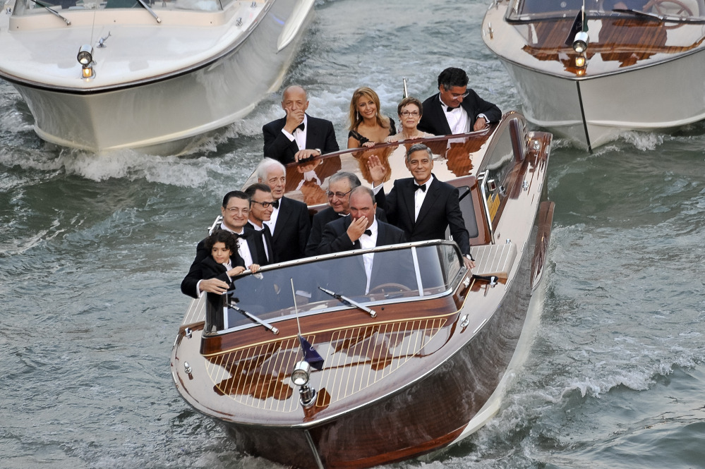 Actor George Clooney, right, waves from a boat with Ramzi Alamuddin, third from right front row, father of her fiancee Amal Alamuddin, his father Nick Clooney, fourth from right front row, and his mother Nina Bruce, second from right back row on their way to the Aman hotel ahead of his wedding in Venice, Italy, on Saturday.