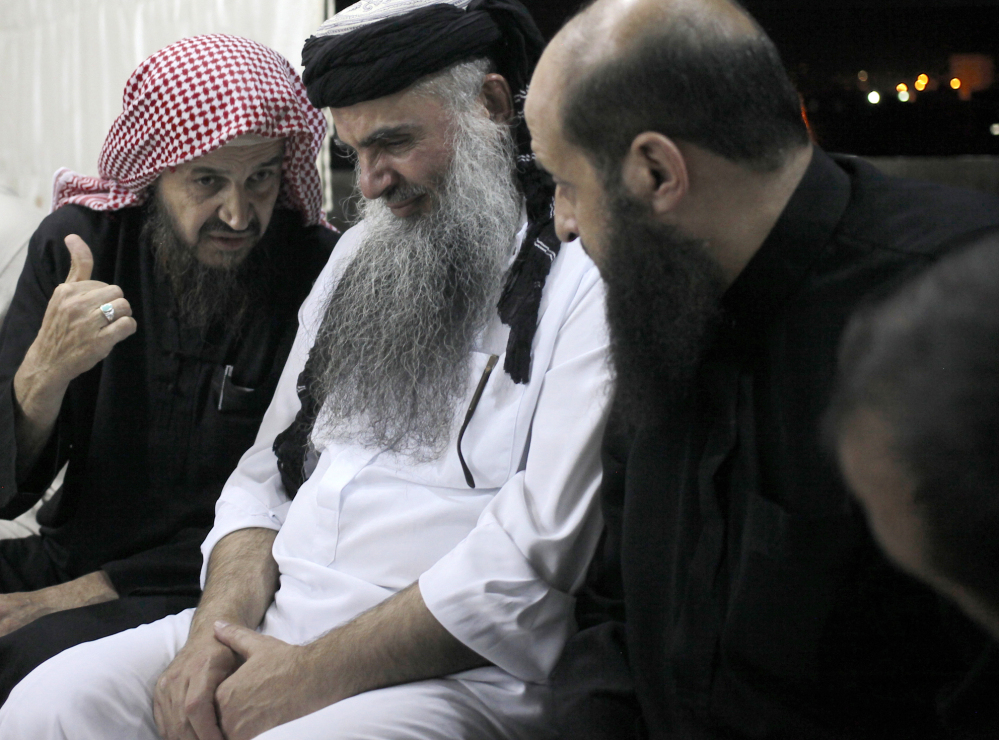 In this Wednesday, Sept. 24, 2014 photo, Radical al-Qaida-linked preacher Abu Qatada, second right, listens to the renowned jihadi ideologue, Abu Mohammed al-Maqdisi, left, on the day Abu Qatada was released from a Jordanian prison after an acquittal on security charges, in Amman, Jordan. Abu Qatada and al-Maqdisi have denounced some of the Islamic State group’s practices as un-Islamic.
