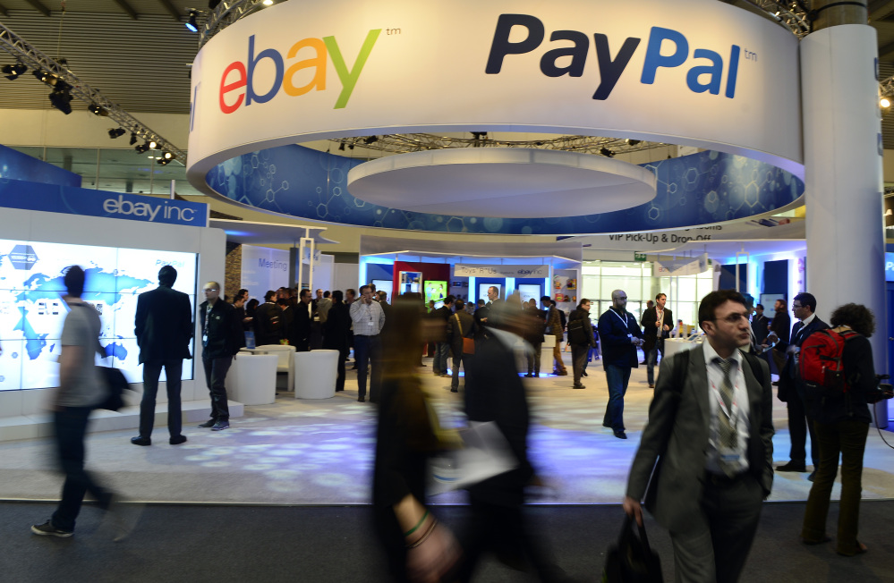 In this Wednesday, Feb. 27, 2013, file photo, attendees walk in front of an EBay and PayPal display area at the Mobile World Congress, the world’s largest mobile phone trade show, in Barcelona, Spain.