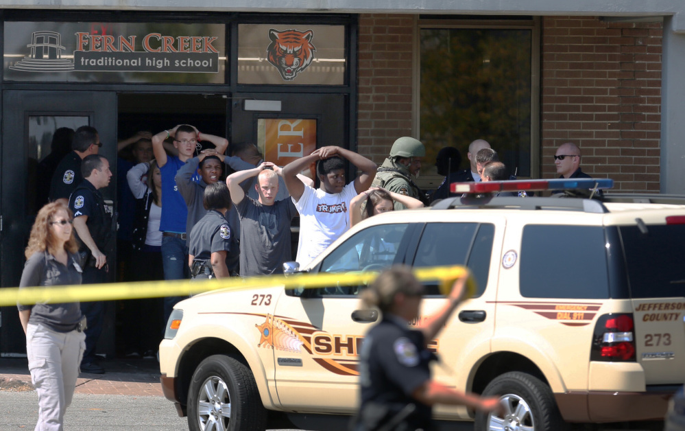 Students put their hands on their heads as they are out of Fern Creek High School in Louisville, Ky., on Tuesday.