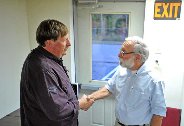 Mike Perkins, left, says farewell to Peter Nielsen, Oakland town manager, after a town meeting at the Oakland town office on Wednesday.