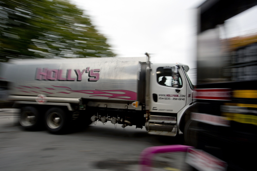 An oil delivery truck moves past a gas pump Wednesday at Holly’s Super Gas on Main Street in Westbrook. Increased domestic production of crude oil has driven down the average price of home heating oil in Maine to $3.32 per gallon, the lowest in more than two years, according to a survey.