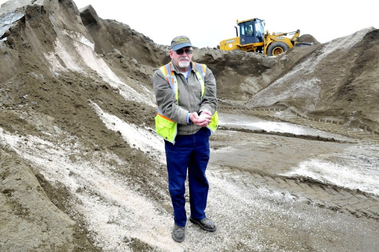 Winslow Public Works Director Paul Fongenie holds a handful of winter road salt Wednesday as employee Tony Rossignol mixes salt and sand at the Winslow department.