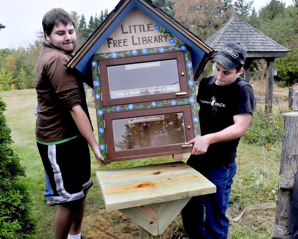 Unity College students and volunteers Thomas Ciarlante, left, and Brett Skelly place a Little Free Library structure on a post at Triplet Park in Unity on Saturday. The work was part of the Unity Barn Raisers’ annual Day of Service. Community members worked on the organization’s gardens, trails, fall clean-up projects and a pig roast dinner.