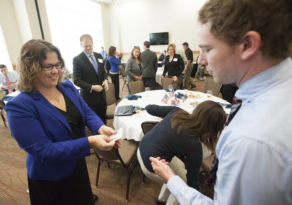 Emily Cain hands out business cards to Matt McLaughlin in September during a candidate luncheon for Fusion Bangor, a business organization, at the Cross Insurance Center in Bangor.