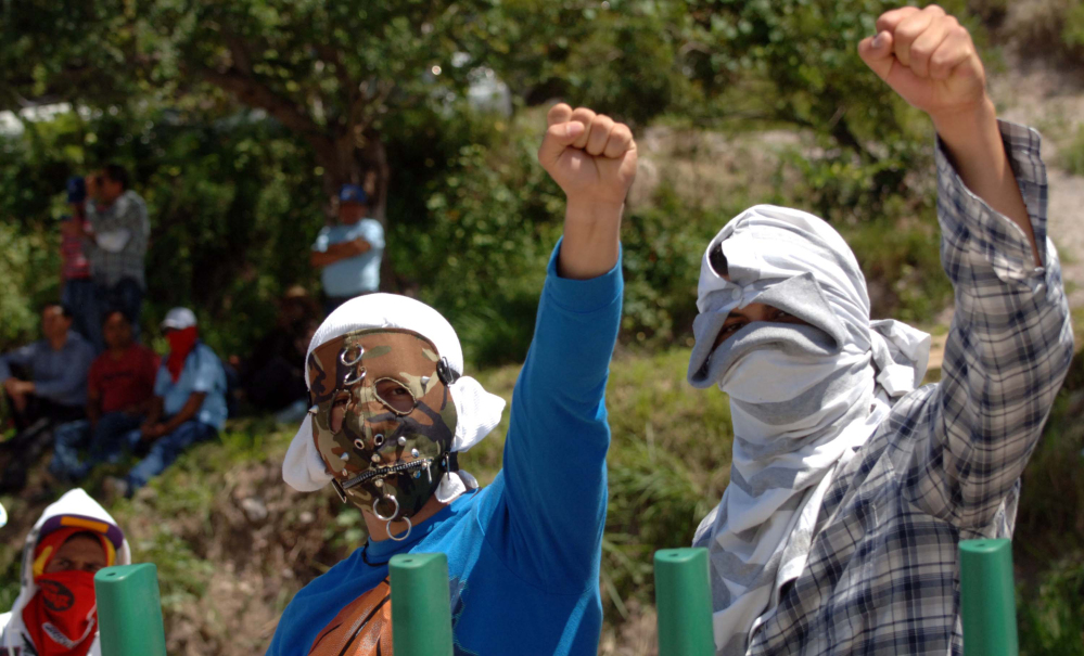 Masked students raise their fists as they block a main highway in Chilpancingo, Mexico, Sunday.