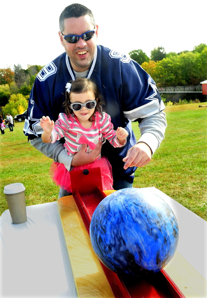 Jimmy Peters helps his daughter Maci with a bowling ball event that was part of the Harvest Festival children games in Waterville on Sunday.