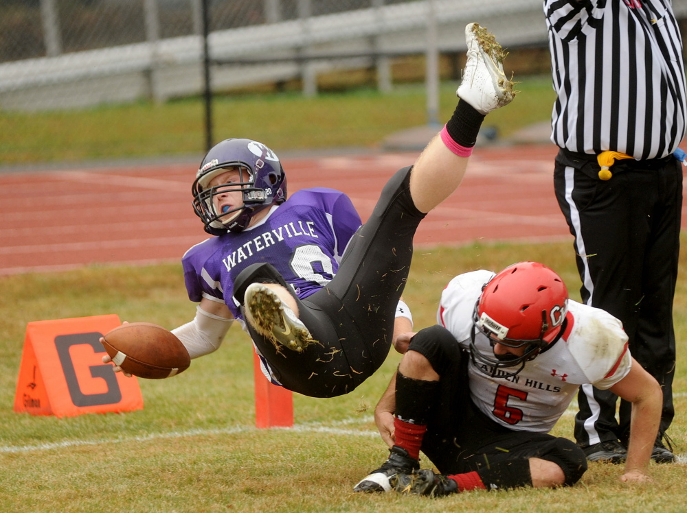 Waterville Senior High School’s Daniel Pooler (20) dives over Camden Hills High School defender Ossian Wienges (6) for the touchdown Saturday in Waterville. Waterville defeated Camden Hills 61-14. While Waterville and Winslow have the top two spots locked up for the Eastern Class C playoffs, a group of teams are fighting for spots 3-6.