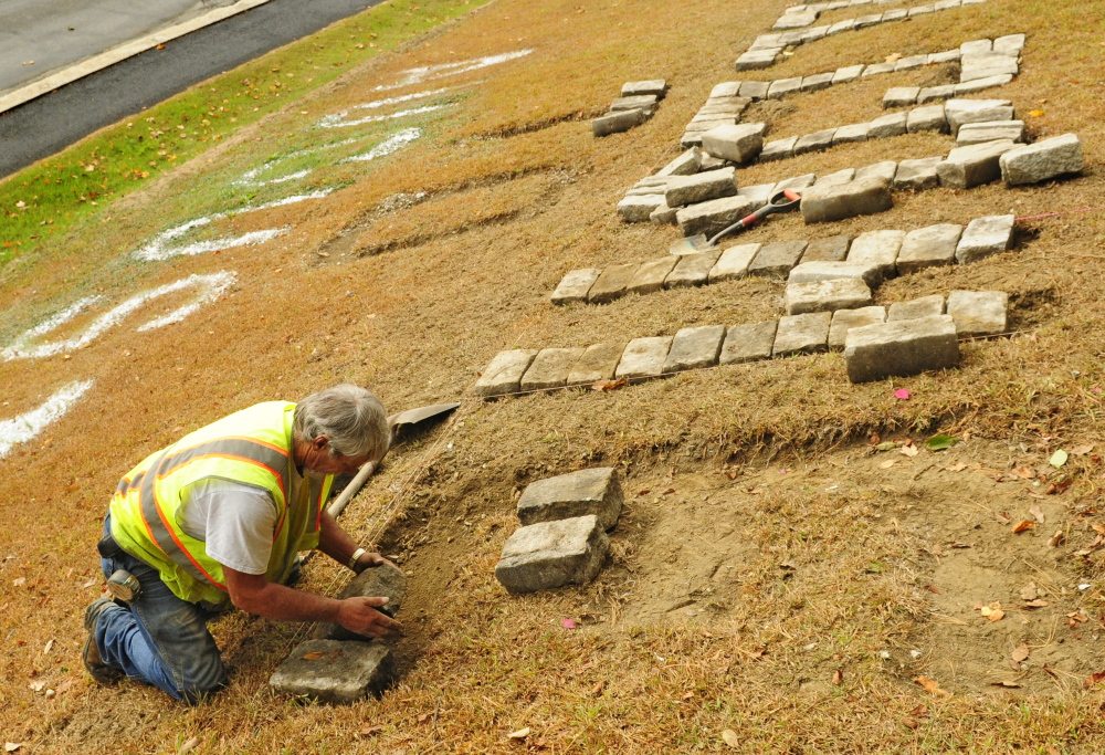 City worker Andy Chavarie sets a granite cobblestone to make a giant letter E in the “Welcome to Augusta” message that’s on Rines Hill, south of downtown Augusta.