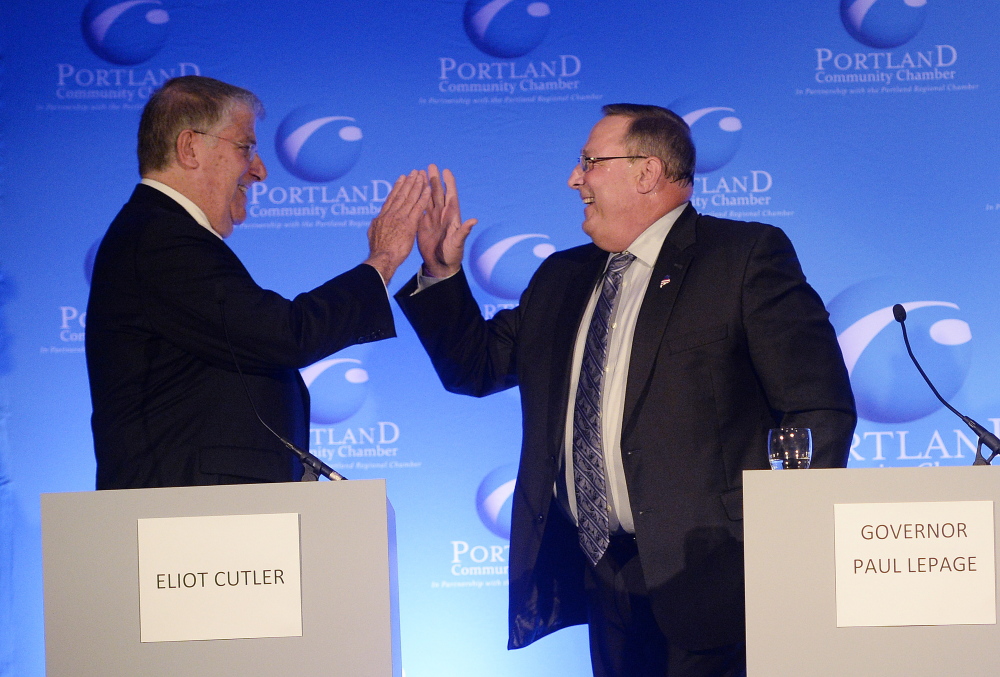 Eliot Cutler and Paul LePage high five each other during the debate at the Holiday Inn by the Bay in Portland Wednesday morning.