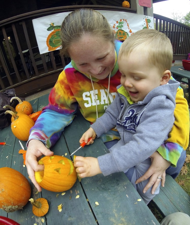 Jennifer Harmon and her 22-month-old son, Dallas Harmon, both of Saint John, New Brunswick, carve a jack-o’-lantern Saturday at the Center for All Seasons during the Belgrade Harvest Festival.