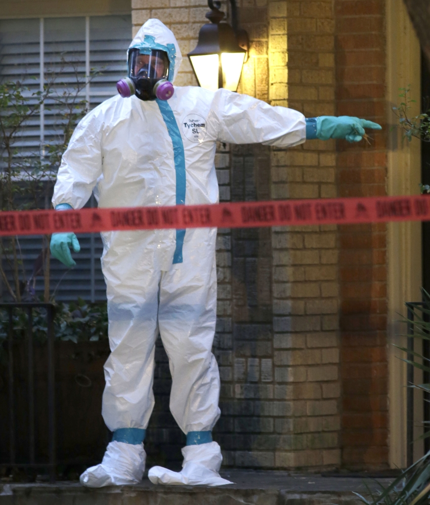 A hazmat worker points to the entrance of an apartment building of a hospital worker, Sunday, Oct. 12, 2014, in Dallas. The Texas health care worker, who was in full protective gear when they provided hospital care for Ebola patient Thomas Eric Duncan, who later died, has tested positive for the virus and is in stable condition, health officials said Sunday. (AP Photo/LM Otero)