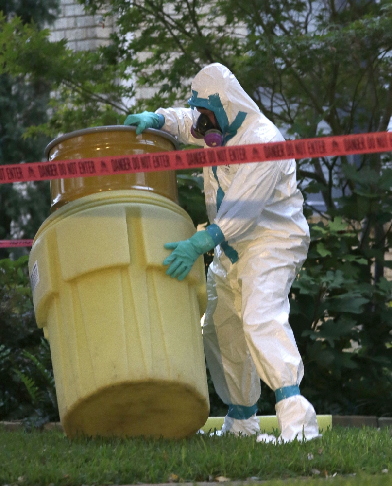 A worker in safety garb packs up a barrel while cleaning outside an apartment building of a hospital worker Sunday in Dallas. The health care worker, who helped care for Ebola patient Thomas Eric Duncan, has tested positive for the virus and is in stable condition.