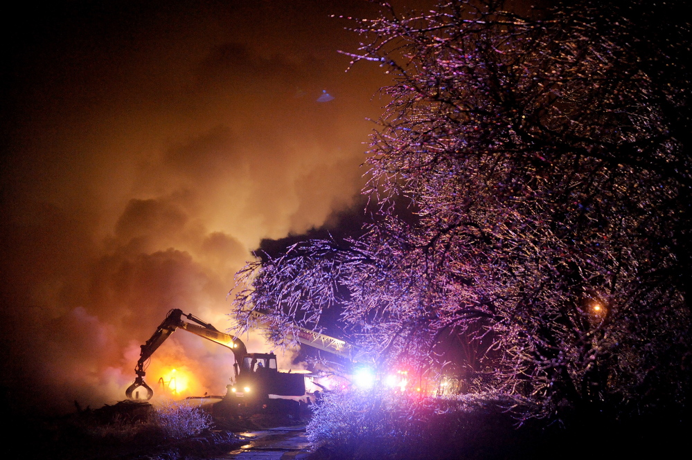 Ice hangs in the trees as an excavator operator sifts through burning rubble where a warehouse burned earlier in the day in Waterville on Wednesday, Dec. 25, 2013. Investigators were on the scene as of 11pm Wednesday and believe improper disposal of stove ash as the cause of the blaze that destroyed the historic building. Cold temperatures and a recent ice storm made investigating the fire more challenging. This photo won first place for the best news photo at the MPA awards.