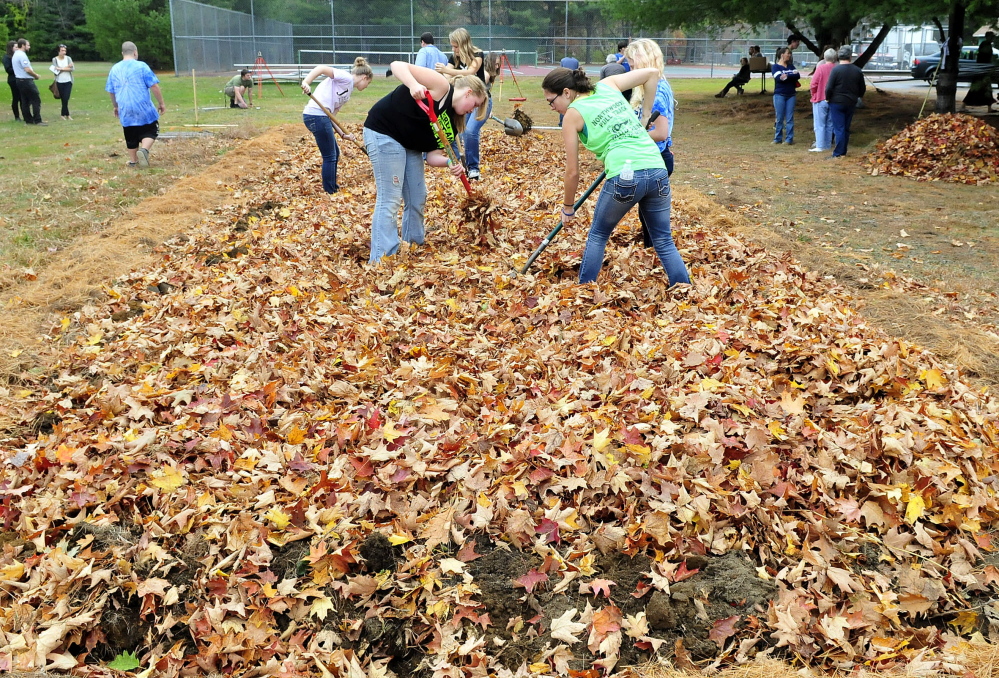 Carrabec High School students work leaves into a school garden plot for mulch. They gathered the leaves earlier as part of a community service project on Wednesday.
