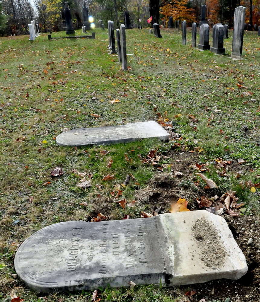 Two grave markers lie toppled by vandals at the Maloon Cemetery in St. Albans on Monday,
