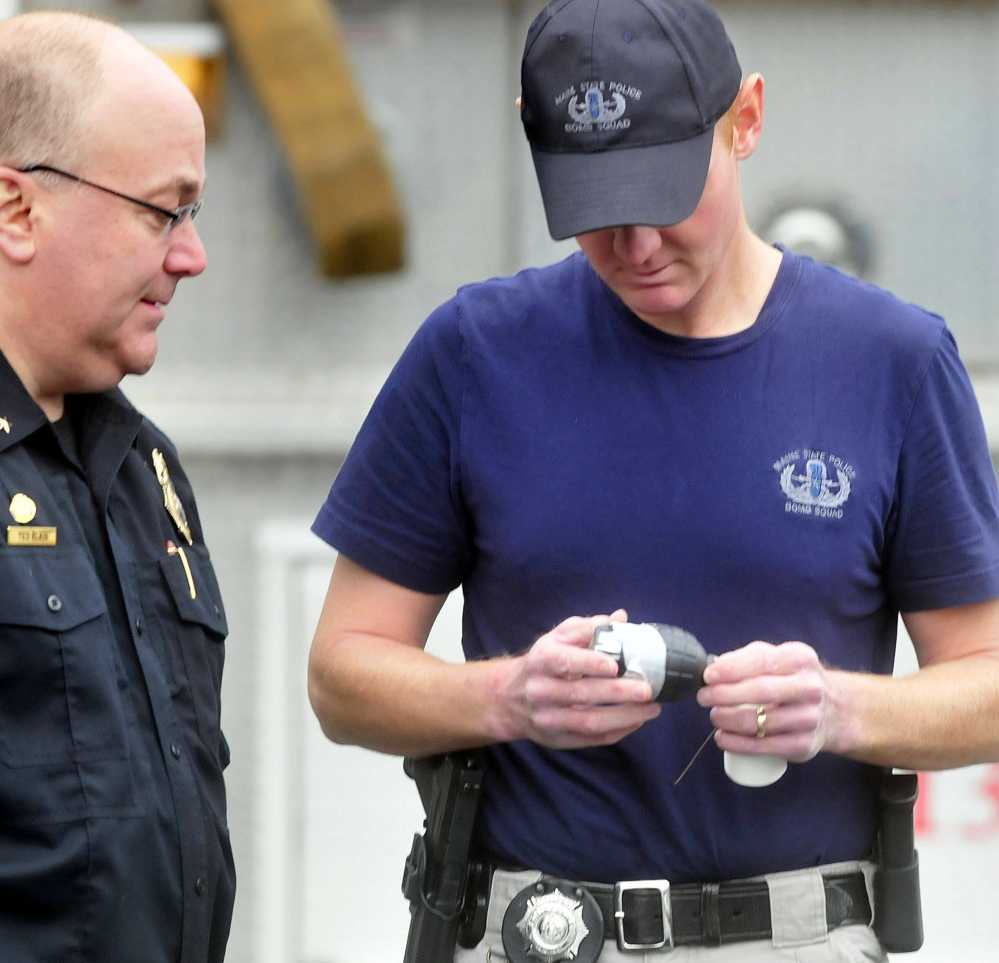 Skowhegan Police Chief Ted Blais, left, looks at a toy held by Trooper Benjamin Sweeney, a member of the state police bomb team, who retrieved the object Tuesday beside the Towne Motel in Skowhegan. The motel was evacuated after an employee discovered the object, which resembles a hand grenade.