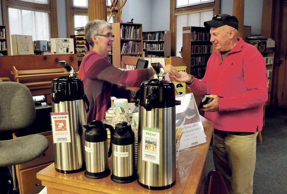 Staff photo by David Leaming
Wilton Free Public Library adult services librarian Lynne Hunter gives change to patron Mike Kane on Tuesday at the front desk. In the foreground are coffee and condiments that are now being offered for sale at the library.