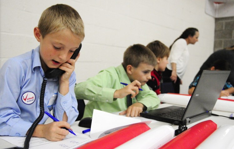 Fort Fairfield Elementary School students Alex Oakes, left, 11, and Chase Coiley, 10, take a turn working at the results station during the mock election rally and tally event on Wednesday at the Augusta Armory.