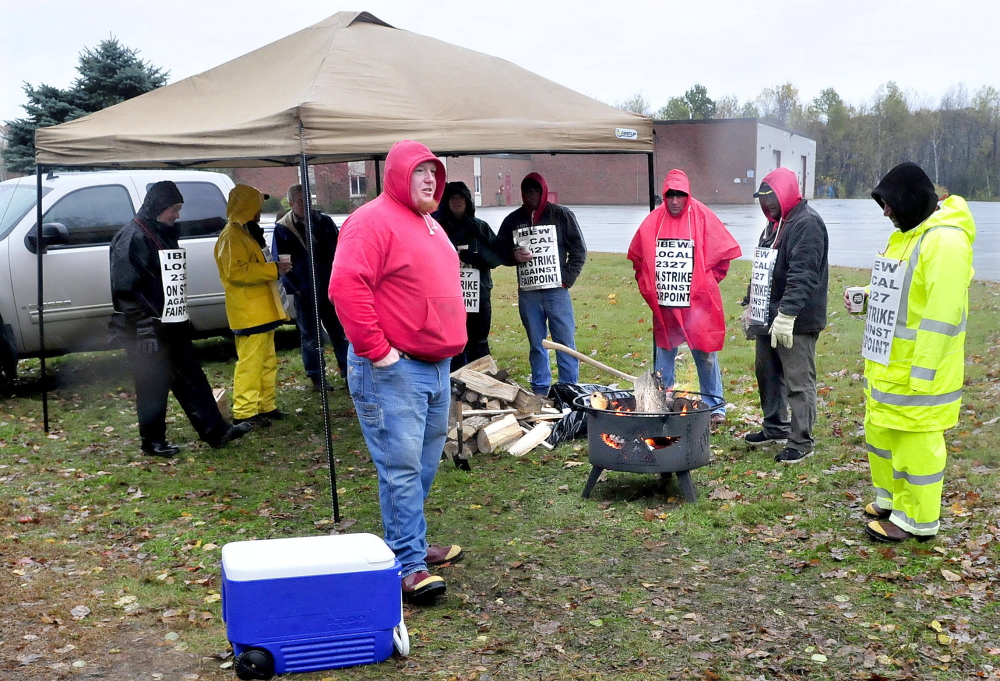 More than a dozen FairPoint employees picket outside the company building in Waterville on Thursday. Todd Foster, center, said the public has shown a lot of support this week by dropping off food, drinks and wood to help the workers stay dry and warm.