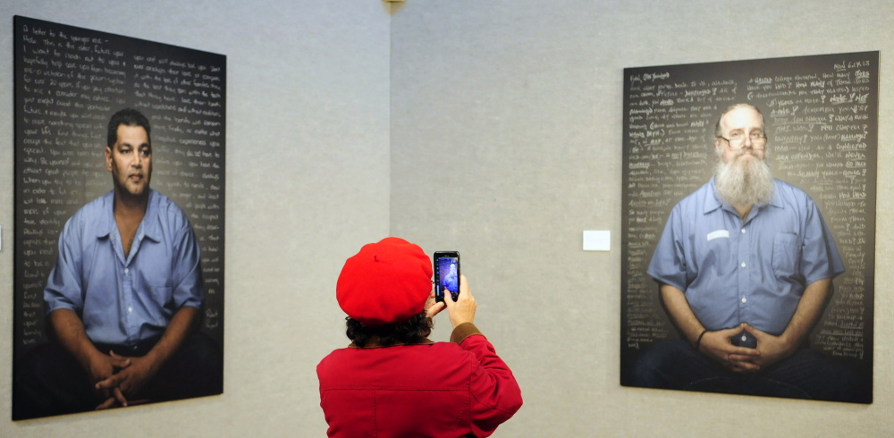 Sandra Chivington snaps a photo of a portrait Thursday during an opening reception at the Danforth Gallery of “Reflect: Convicts’ Letters to Their Younger Selves,” at the University of Maine at Augusta.