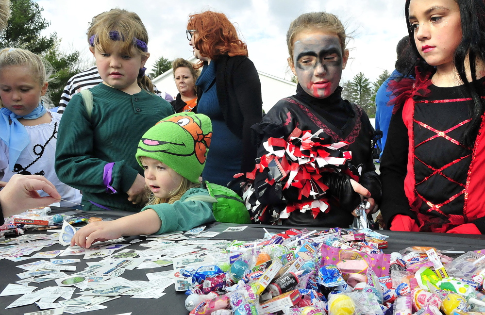 Kids dressed up for Halloween crowd around one of 30 vehicles and owners for candy during the second annual Trunk-or-Treat event at the Canaan Elementary school on Sunday. Jorga Sharp reaches for her choice of candy. The event is billed as a safer alternative to door-to-door trick or treating.