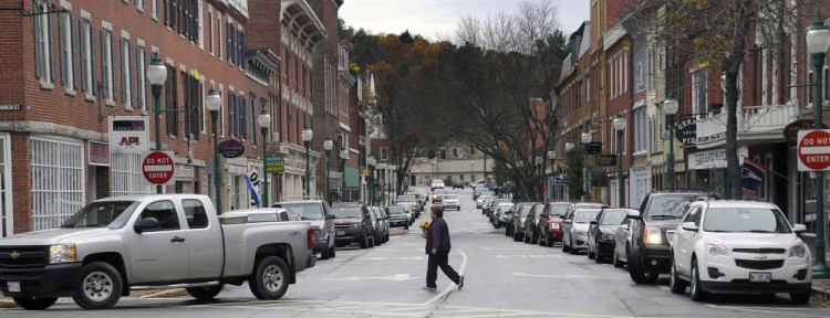 A woman walks across Water Street in Gardiner on Tuesday after shopping at Berry & Berry Floral. Maine Preservation released its annual list of the state’s most endangered historic properties Tuesday, including downtown Gardiner on its list because of concern about flood insurance.