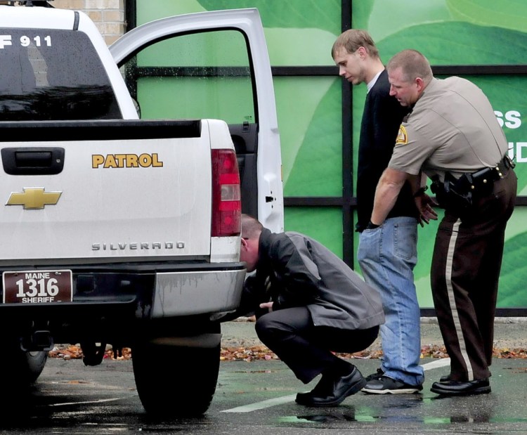 Somerset Deputy Ronnie Blodgett searches a handcuffed man outside the Rite Aid store in Skowhegan following report of a robbery on Wednesday.