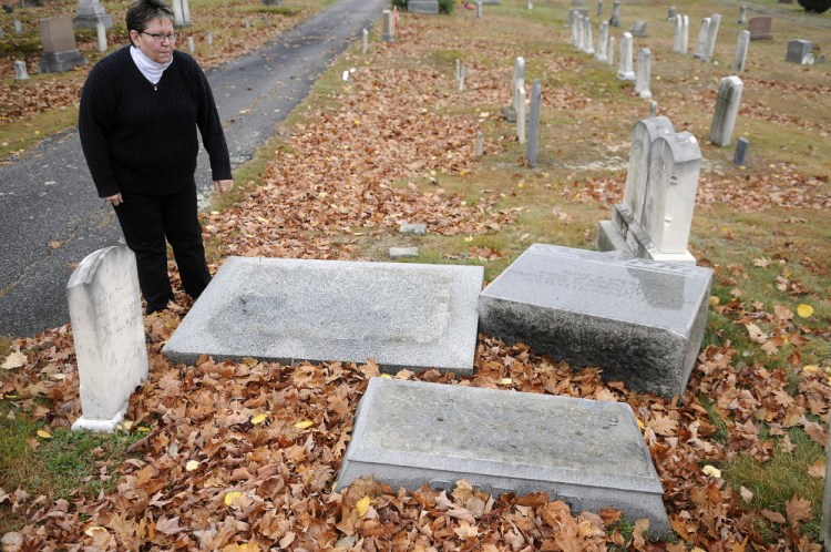 Karen Cyr inspects headstones Wednesday that were damaged after an altercation in the Monmouth Ridge Cemetery more than a year ago.