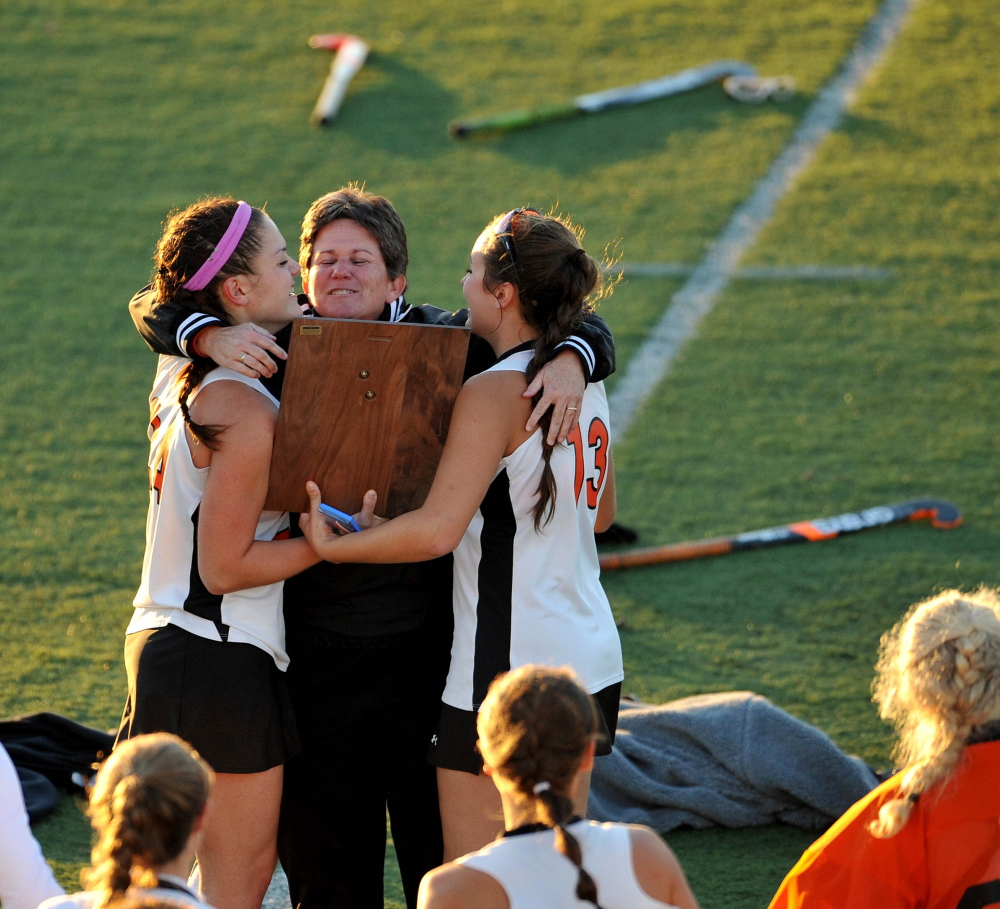 Winslow High School head coach Mary Beth Bourgoin embraces Brooke Haskell, left and Alyssa Wood, after defeating Dexter High School 2-0 Thursday in the Eastern Class C championship game at Hampden Academy.