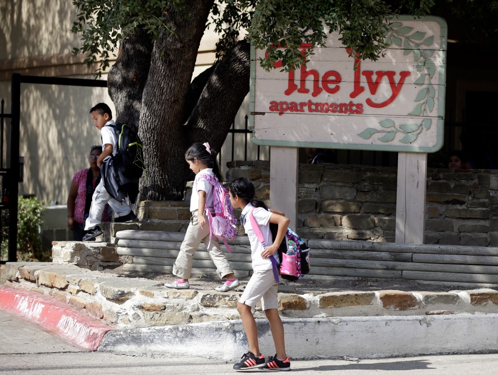 Children arriving home from school walk past the main entrance to The Ivy Apartments complex, Wednesday, in Dallas. The man diagnosed with having the Ebola virus was staying at the complex with family. The Associated Press