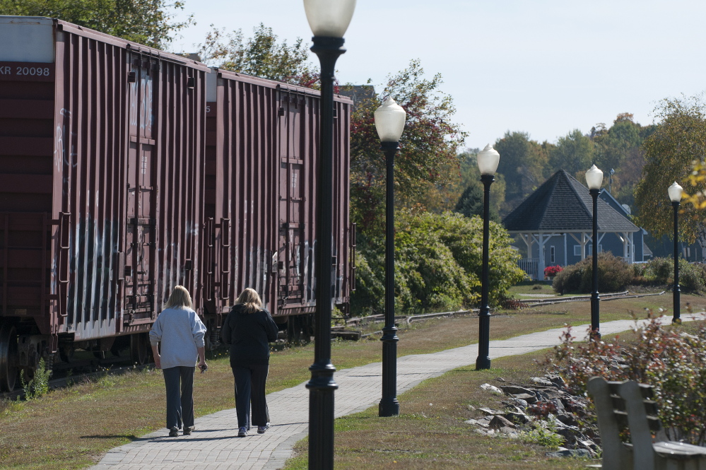 Pam Chaisson, left and Karen Wardwell, right, walk along Bucksport’s waterfront on Thursday. The mill, which anchors one end of the riverfront walkway, names high energy costs as a major factor in the shutdown, though it plans to keep running its adjacent power plant to sell electricity back to the grid. Kevin Bennett/Special to the Press Herald